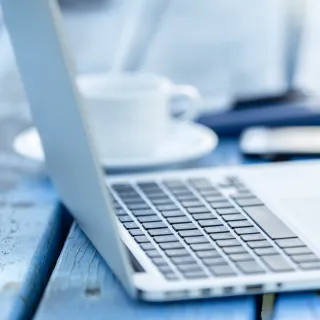 geöffneter Laptop mit Kaffee und Smartphone