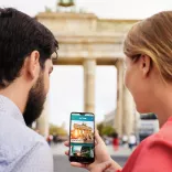 Paar mit neuer App "About Berlin" vorm Brandenburger Tor Paar mit neuer App "About Berlin" vorm Brandenburger Tor