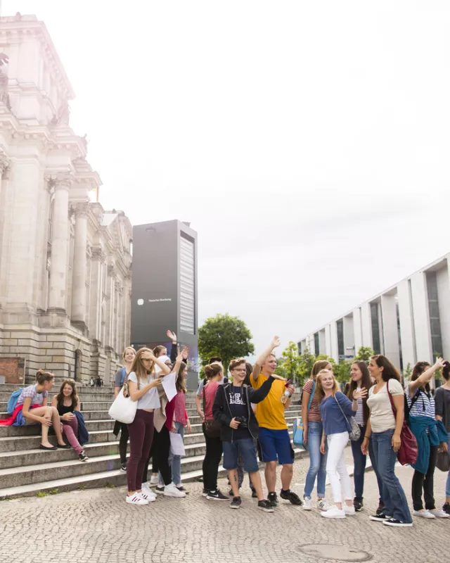 Klassenreise nach Berlin Touristengruppe hinter Berliner Reichstag auf Spree schauend