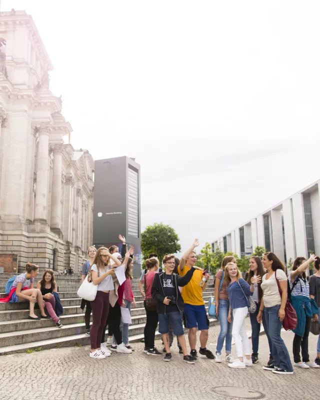 Touristengruppe hinter Berliner Reichstag auf Spree schauend