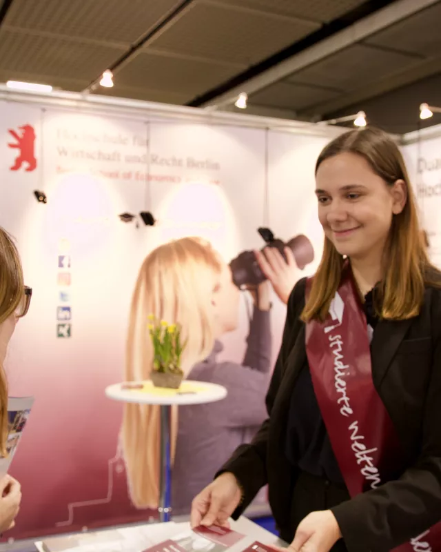 Messebesucher redet mit Standbetreuung der studierten Weltenbummler