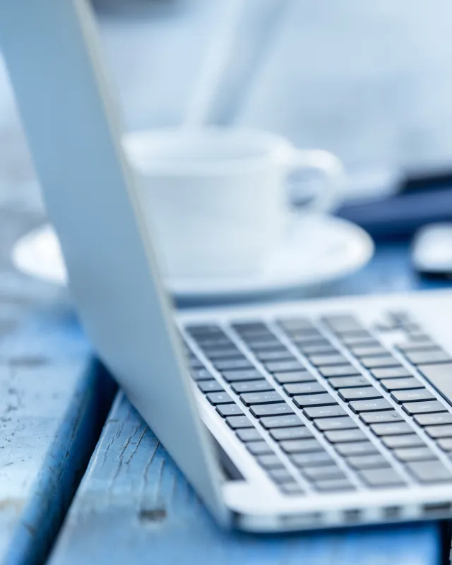 geöffneter Laptop mit Kaffee und Smartphone