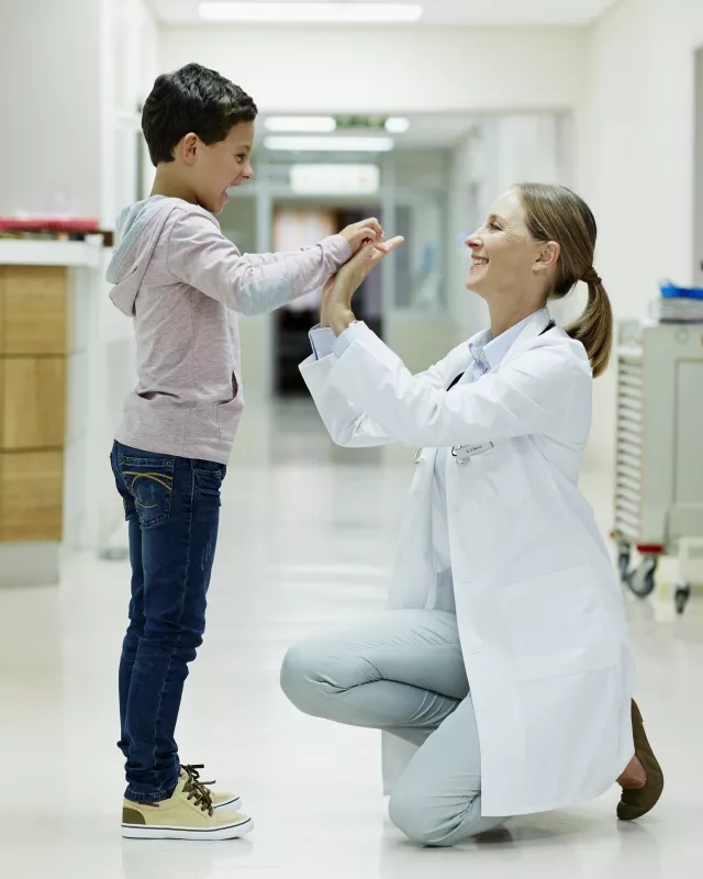 Doctor giving high-five to boy in corridor