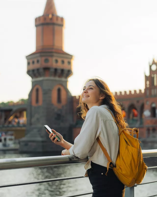Junge Frau mit Smartphone vor der Oberbaumbrücke