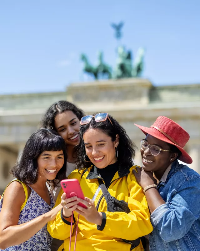 Multiracial group of women friends on vacation looking at their pictures on a smart phone