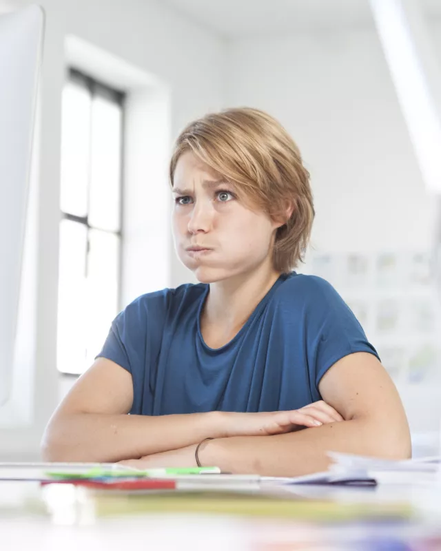Portrait of young woman pouting a mouth at her desk in a creative office