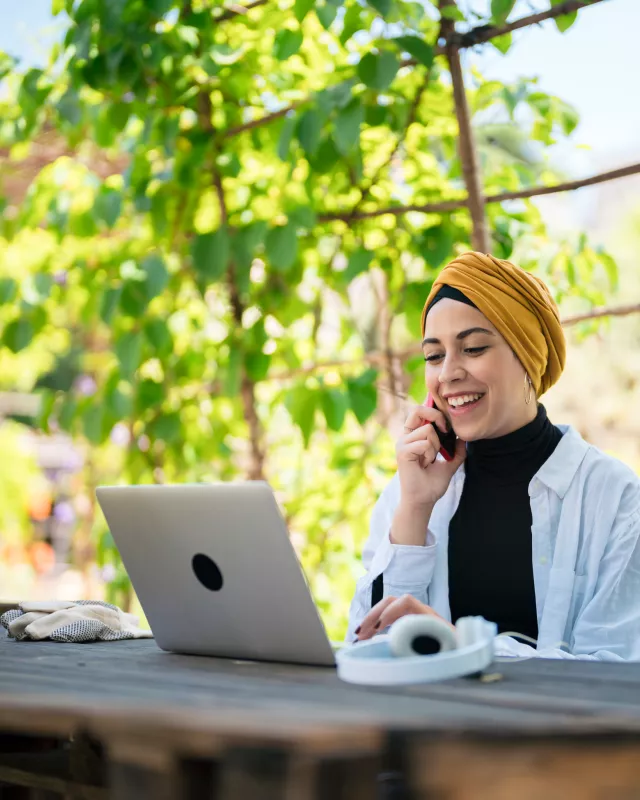 Content Muslim freelancer talking on smartphone in garden