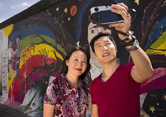 chinesische Touristen in Berlin vor der East-Side-Gallery
