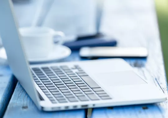 geöffneter Laptop mit Kaffee und Smartphone