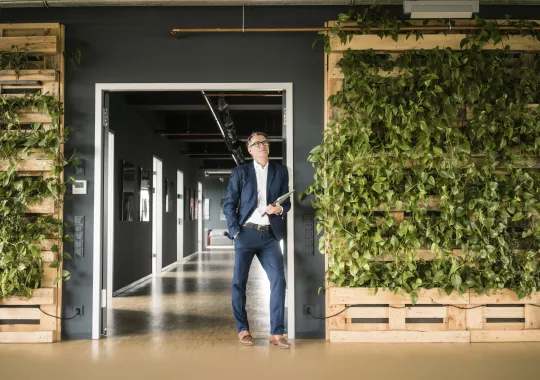 Mature businessman with laptop standing in green office