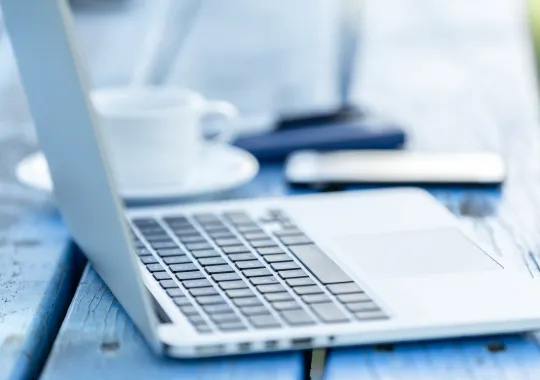 geöffneter Laptop mit Kaffee und Smartphone