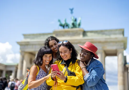 Multiracial group of women friends on vacation looking at their pictures on a smart phone