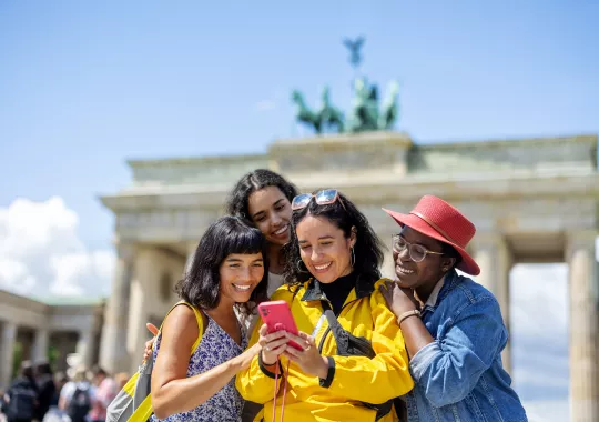 Multiracial group of women friends on vacation looking at their pictures on a smart phone