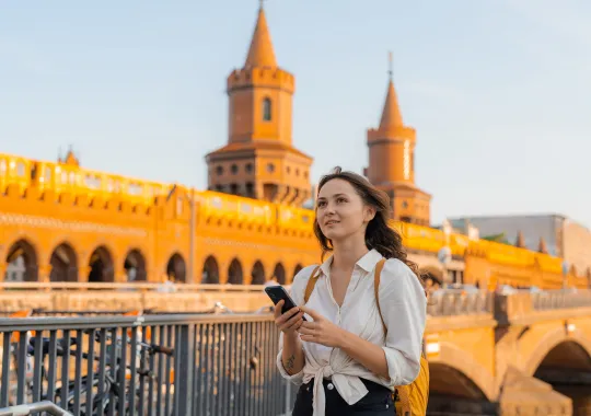 Frau mit Smartphone vor Oberbaumbrücke
