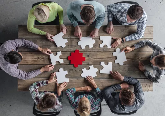Menschen an einem Tisch mit Puzzleteilen