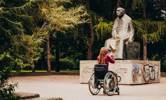 Frau im Rollstuhl fotografiert Statue im Park