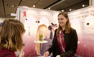 Messebesucher redet mit Standbetreuung der studierten Weltenbummler