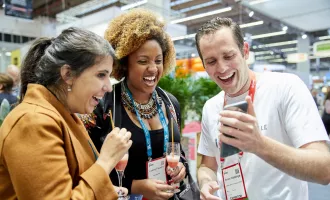 Drei Menschen die auf ein Handy gucken und lachen