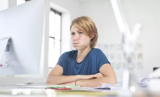 Portrait of young woman pouting a mouth at her desk in a creative office