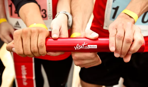 4 Hände an einem Staffelstab