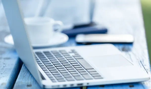 geöffneter Laptop mit Kaffee und Smartphone