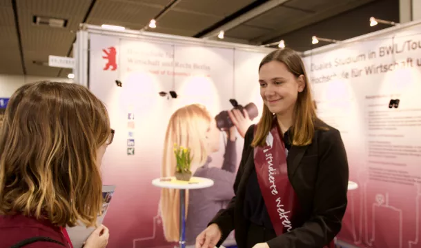 Messebesucher redet mit Standbetreuung der studierten Weltenbummler