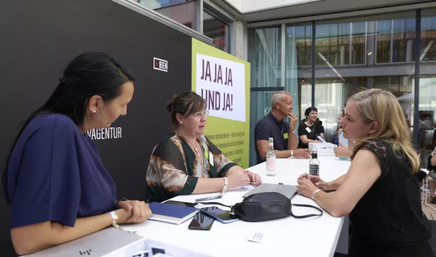 Menschen die an einem Tisch zusammen stehen und sich unterhalten