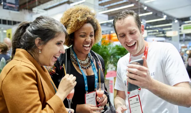 vistBerlin auf der IMEX Drei Menschen die auf ein Handy gucken und lachen