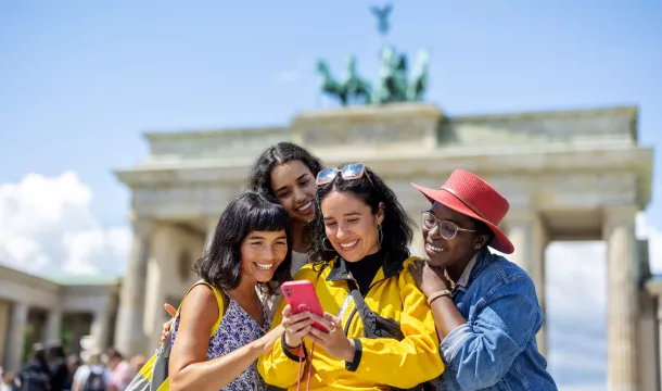 Multiracial group of women friends on vacation looking at their pictures on a smart phone