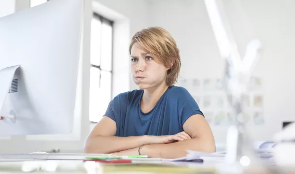 Portrait of young woman pouting a mouth at her desk in a creative office