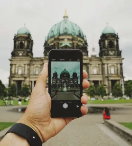 Hand mit Handy in Hand, auf Screen Berliner Dom, im Hintergrund Berliner Dom