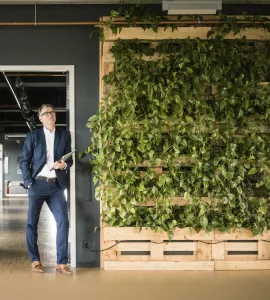 Mature businessman with laptop standing in green office