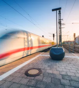 White high speed train in motion on the railway station at sunset. Germany. Blurred modern intercity train on the railway platform. Industry. Passenger train on railroad. Railway travel in Europe