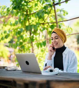 Content Muslim freelancer talking on smartphone in garden