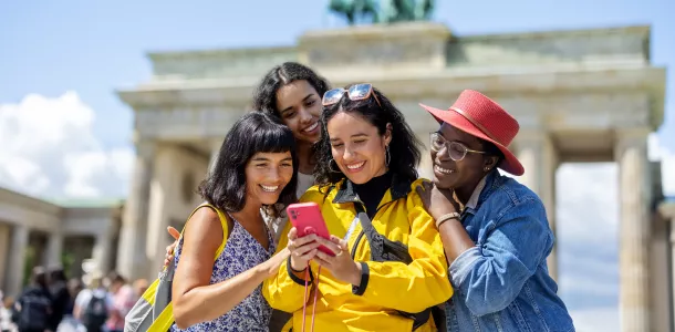 Multiracial group of women friends on vacation looking at their pictures on a smart phone