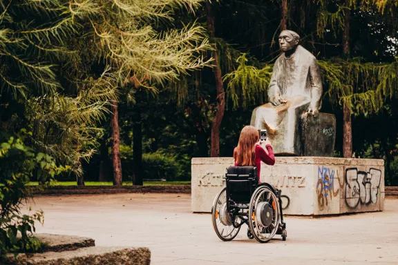 Frau im Rollstuhl fotografiert Statue im Park