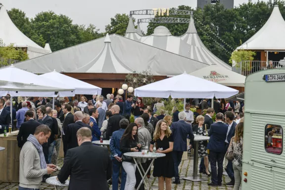 DEHOGA - Sommerfest Tipi am Kanzleramt im Hintergrund, Menschen an Stehtischen, weiße Schirme, vorne rechts Teil eines Food Trucks