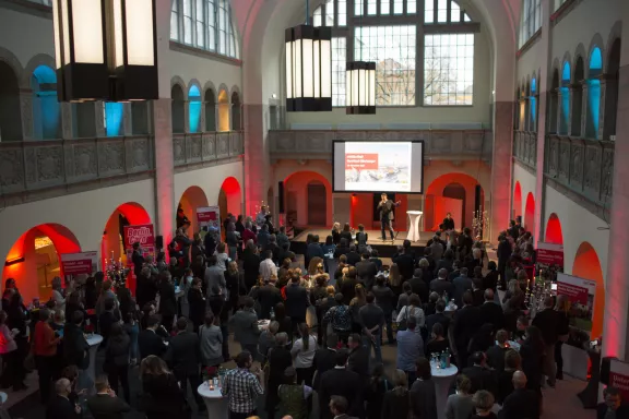 Stadtbad Oderberger, Blick von Galerie auf Leinwand und Bühne, Partner stehen vor Bühne, Bogengang rot beleuchtet