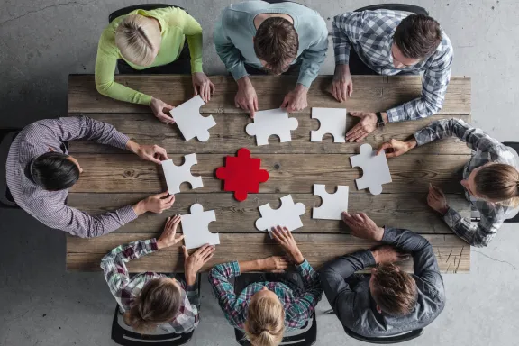 Menschen an einem Tisch mit Puzzleteilen